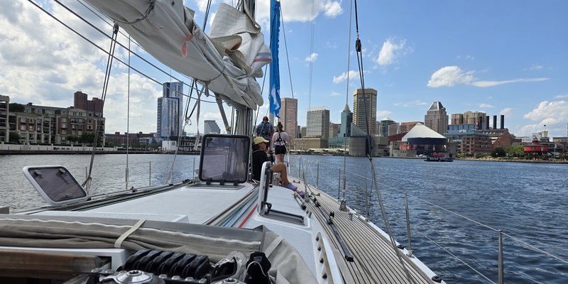 Blick vom Segelschiff aus auf städtische Skyline mit heruntergelassenem Segel