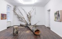 Ausstellungsansicht der KünstlerinMonilola Olayemi Ilupeju: liegender Baumstamm, innen hohl, gefüllt mit Ziegeln, in einem weißen Zimmer