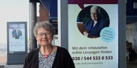 Margret Hampel vor Werbedisplay mit Werbung vom Infotelefon