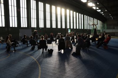 Schmuckbild - Menschen sitzen im Gegenlicht in einer Halle
